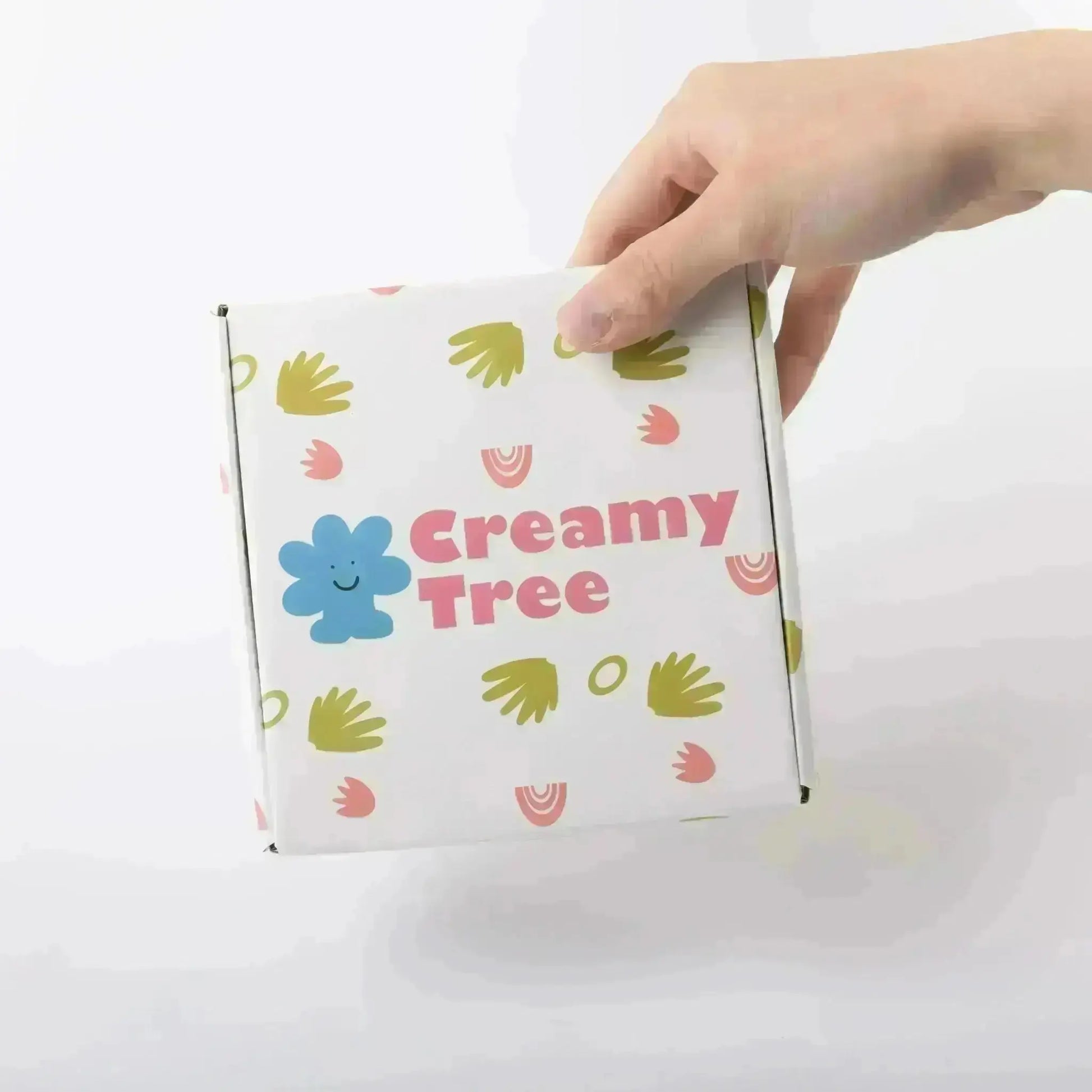 Close-up of a hand holding the Creamytree box with decorative patterns and a blue logo