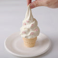 A hand squeezing Creamy Tree Vanilla Ice Cream Cone Squishy Toy