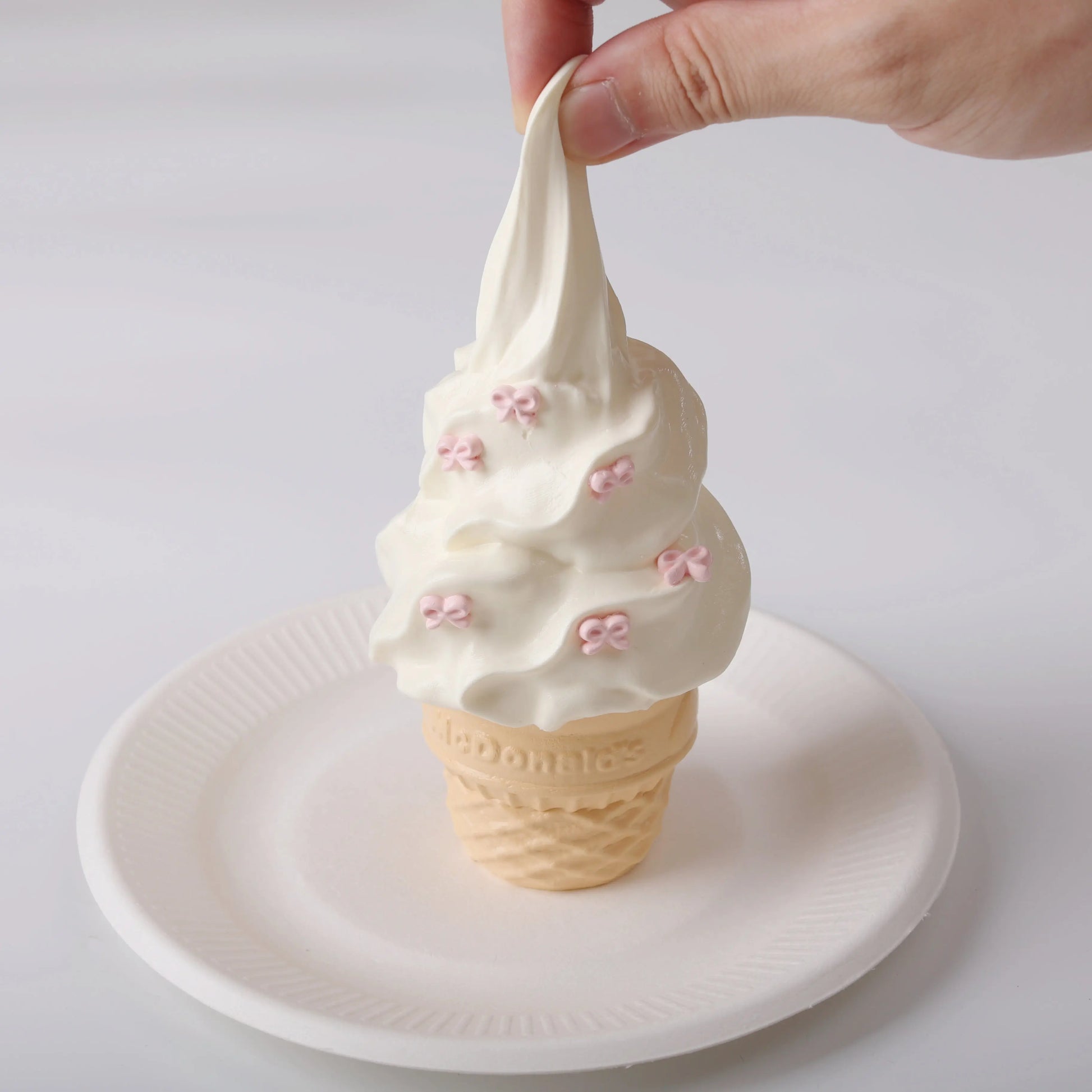 A hand squeezing Creamy Tree Vanilla Ice Cream Cone Squishy Toy