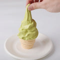 A hand squeezing Creamy Tree Matcha Ice Cream Cone Squishy Toy