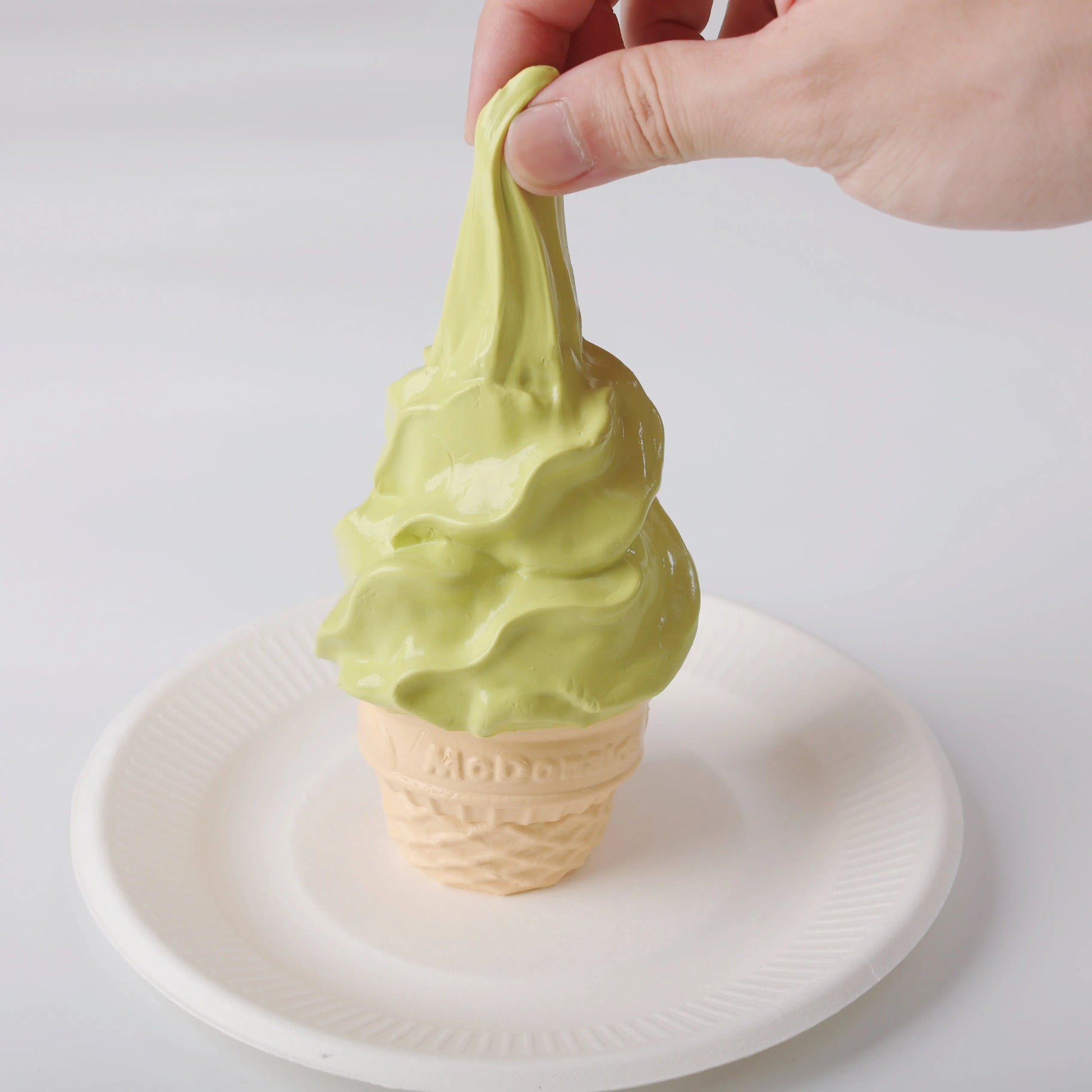 A hand squeezing Creamy Tree Matcha Ice Cream Cone Squishy Toy