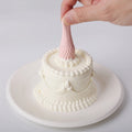 A hand is squeezing the pink strawberry on the Elodie Pink Strawberry Cake Squishy