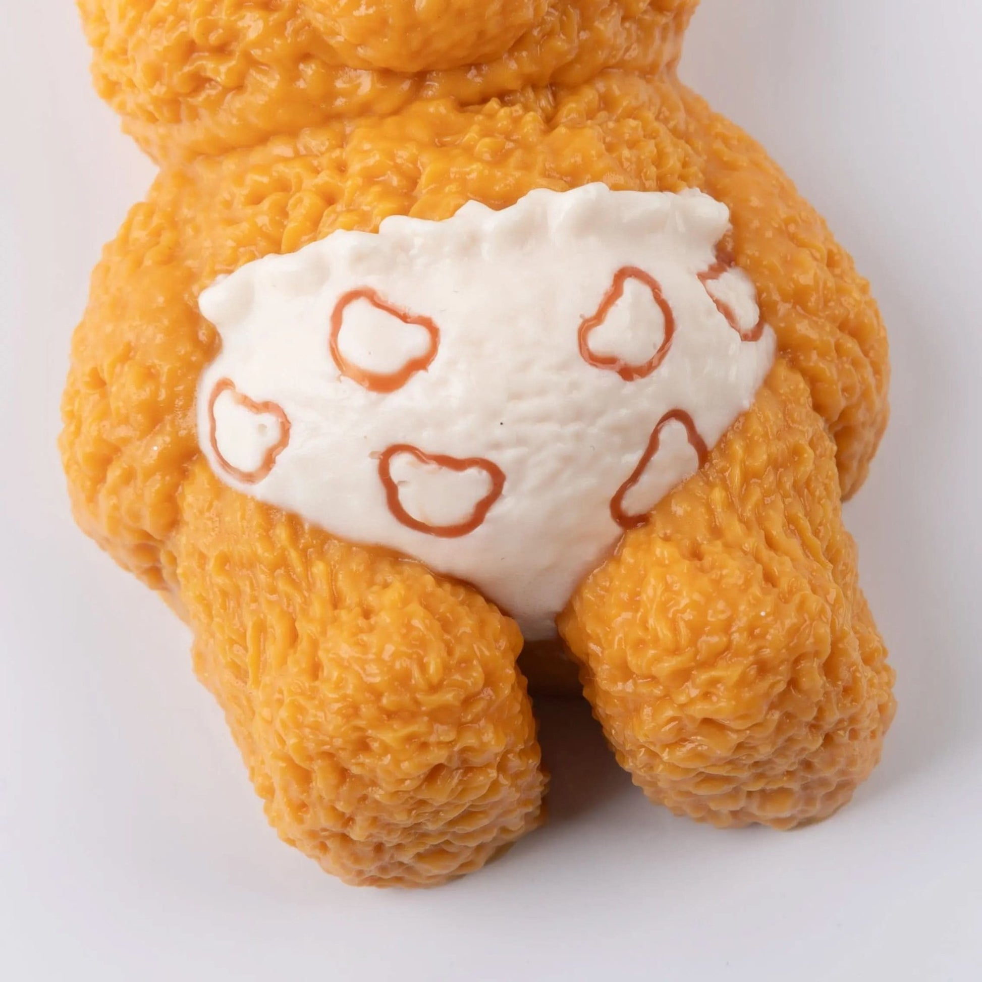 Close-up of orange Creamy Tree stress toy bear wearing a white diaper with heart shapes