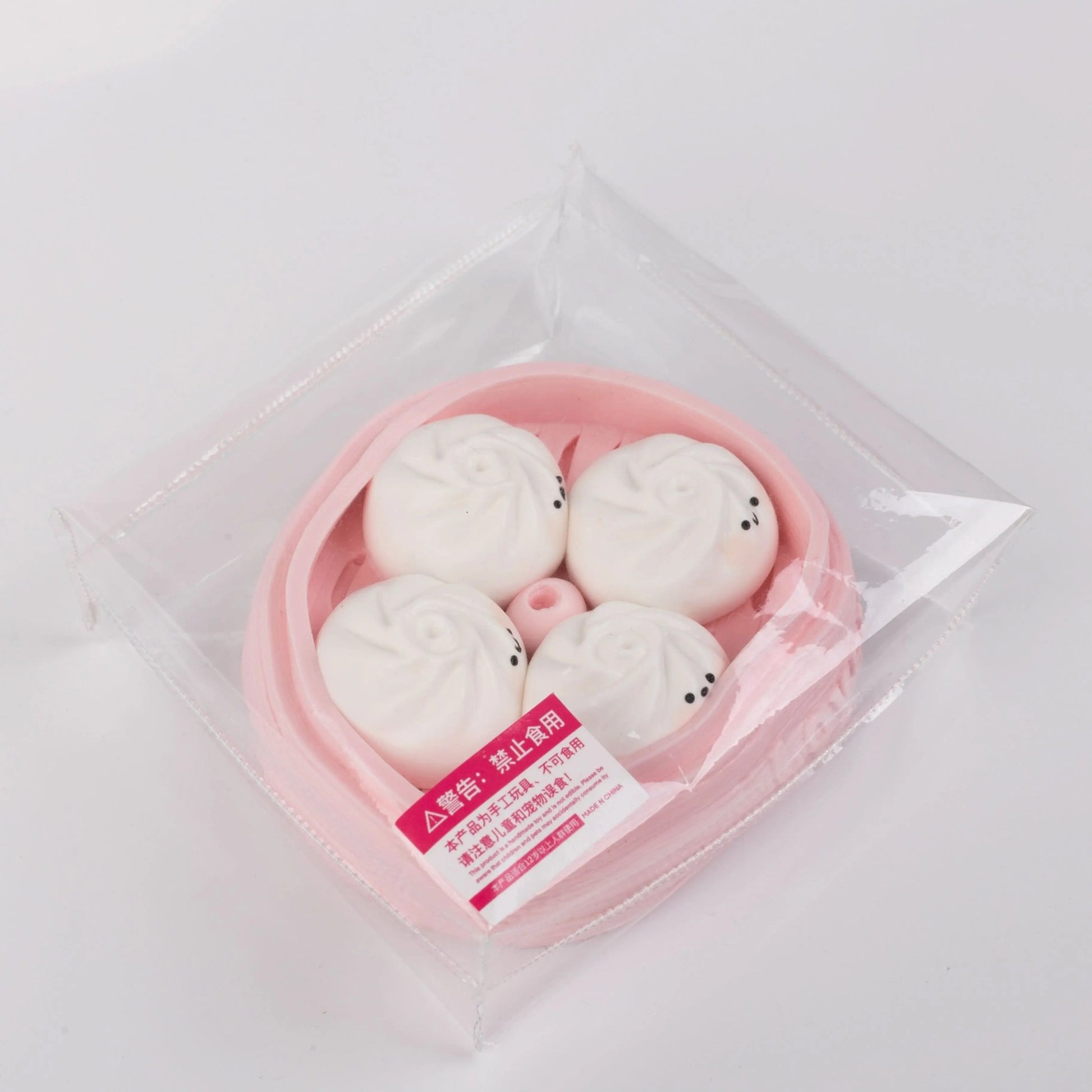 Side view of Creamy Tree Pink and White Dumplings Squishy toy with safety label